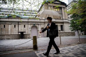 FILE PHOTO: FILE PHOTO: Office employee walks in front of the bank of Japan building in Tokyo