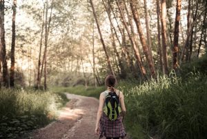 rear-vie-woman-walking-dirt-road-forest-1758522280-821x550
