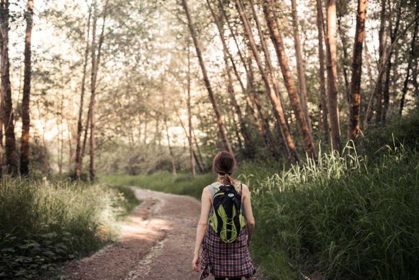 rear-vie-woman-walking-dirt-road-forest-1758522280-821x550