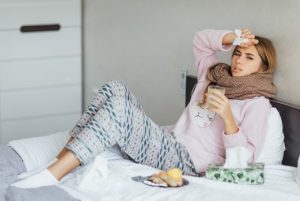 young-woman-sick-bed-with-temperature-drinks-hot-tea-touching-her-head-1764403883-821x550